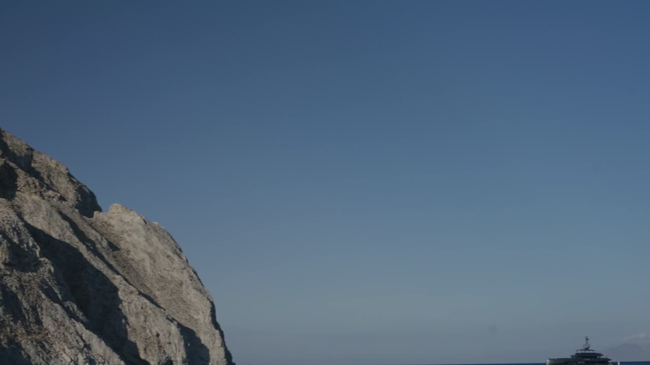 그리스 산토리니의 바다에 있는 메가 요트 근처의 큰 산