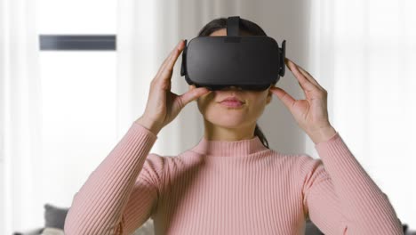 mujer poniendo auriculares de realidad virtual en el salón en casa