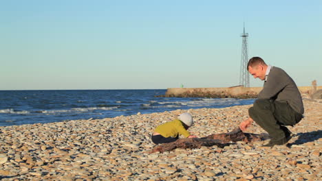 padre e hijo jugando en la playa de guijarros