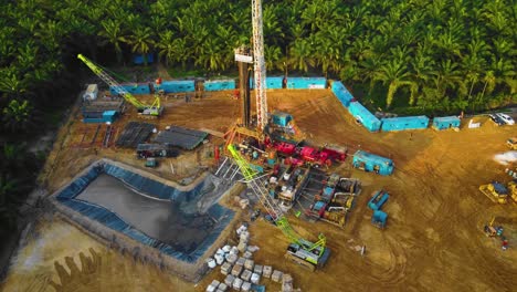 Cinematic-4K-Drone-Footage-of-Onshore-Drilling-Rig-equipment-structure-for-oil-exploration-and-exploitation-in-the-middle-of-jungle-surrounded-by-palm-oil-trees-during-sunset-and-high-oil-price