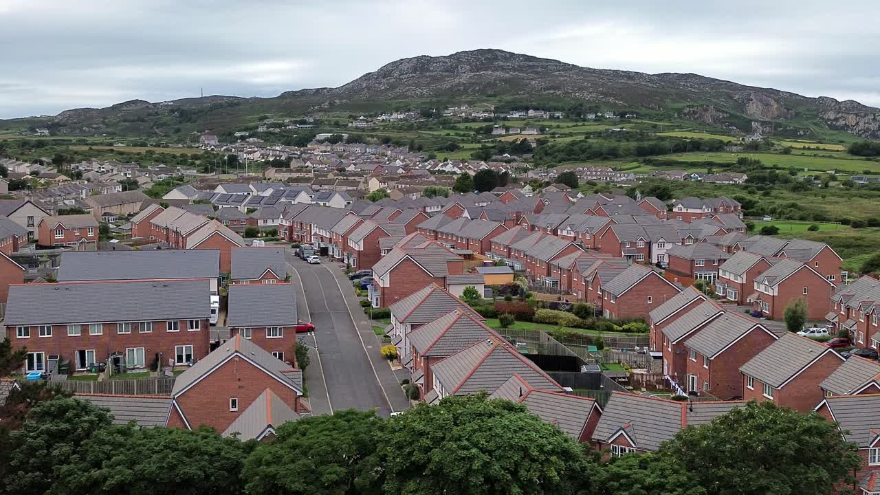 Aerial view across modern red brick housing neighbourhood under Holyhead mountain in Wales