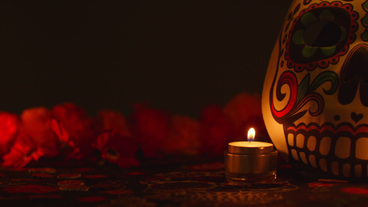 vida muerta de cráneo y máscara decorados rodeados de velas y flores celebrando la fiesta mexicana de dia de muertos o día de los muertos contra un fondo oscuro