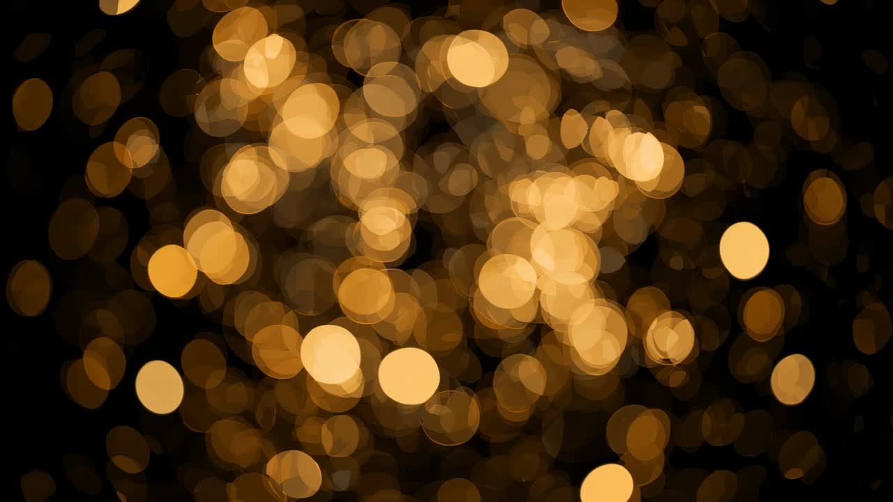 Shifting cluster of warm bokeh disks moving across dark background, lens motion causing shimmer