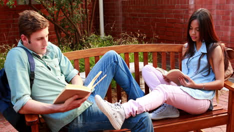 dos estudiantes sentados en un banco revisando