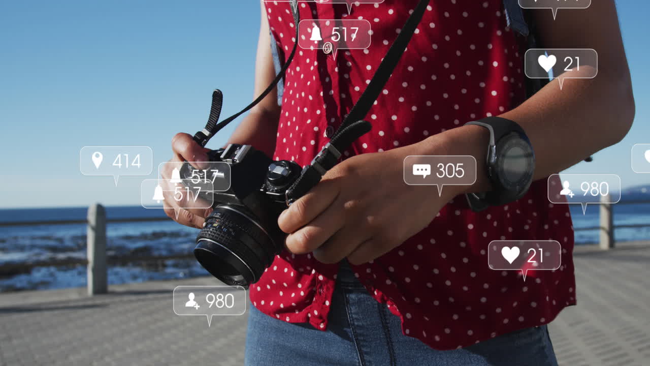 múltiples burbujas de habla con iconos digitales contra una mujer afroamericana con una cámara digital