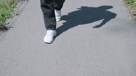 young man walking with guitar on street near forest