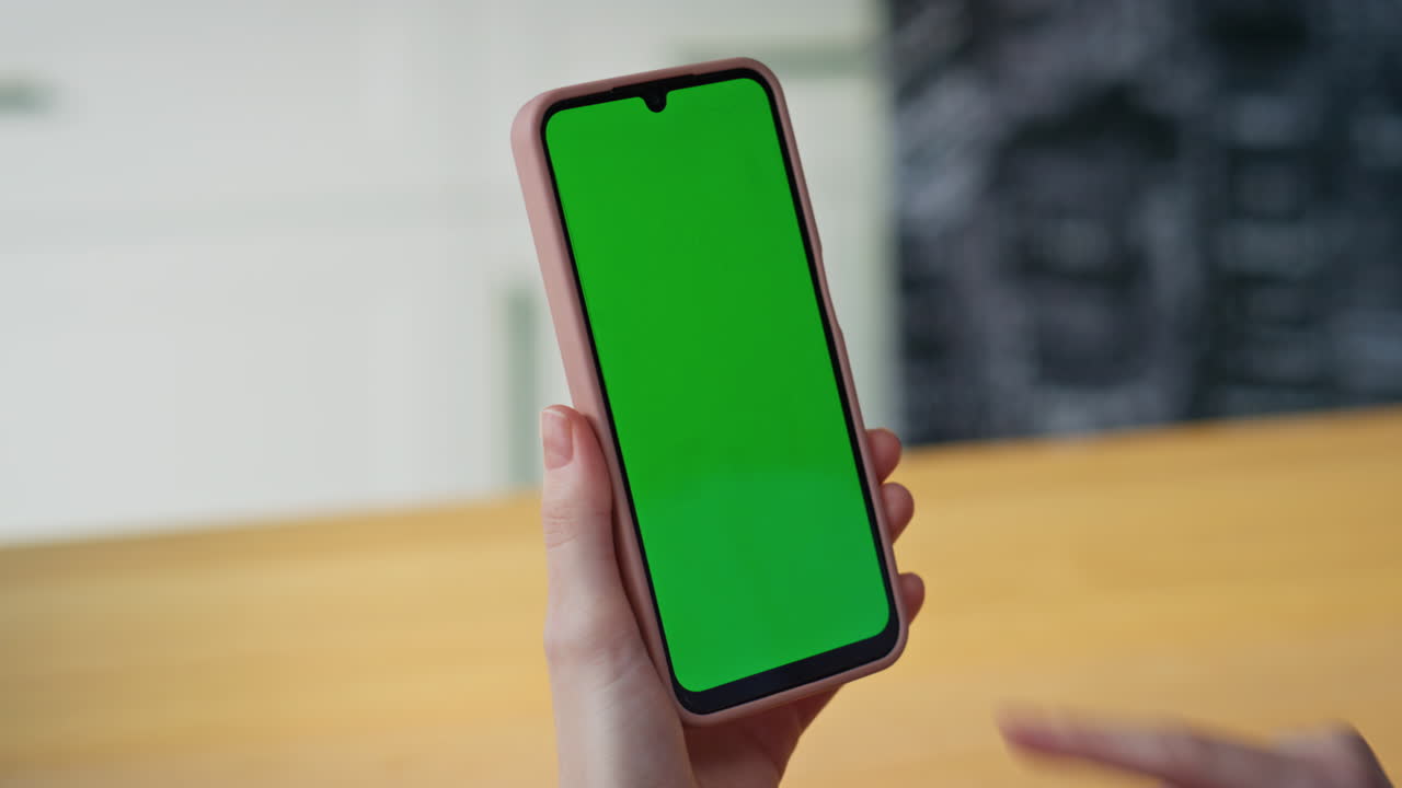 Ragazza sconosciuta che tocca uno smartphone con greenscreen leggendo un messaggio in casa, primo piano