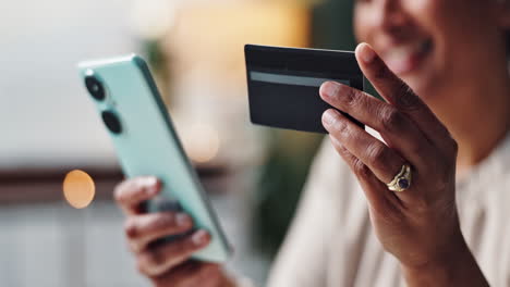 person holding a credit card and using a mobile phone