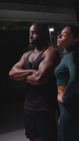 vertical video portrait of determined male and female athletes in in fitness clothing shot in gym with low key lighting 1