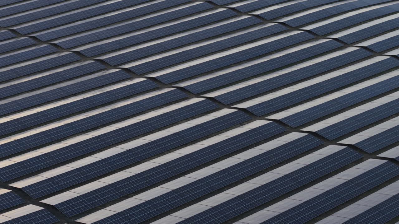 This sweeping aerial view captures a peaceful moment at a solar power farm in Bulgaria. With the sun low on the horizon, the panels shine with reflections of eco-friendly energy production.