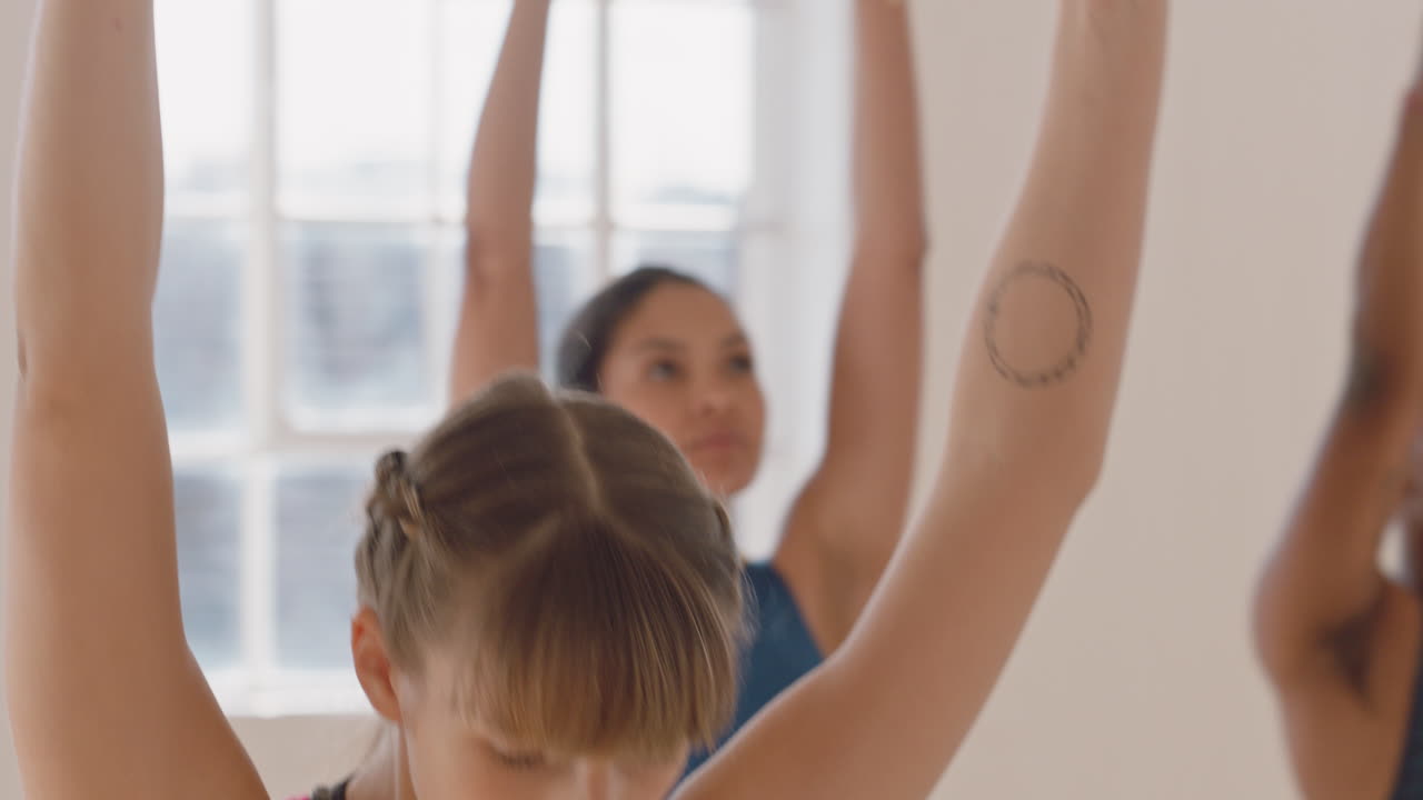 lezione di yoga sana donna caucasica che pratica la posa del guerriero godendo dello stile di vita fitness esercitandosi con persone multietniche in studio di allenamento