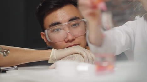 teacher looks at student doing experiment with liquids