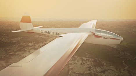 An-aerial-view-of-the-white-sailplane-with-no-propeller-calmly-gliding-in-the-sky,-over-snow-covered-mountains.-Flying-aerodynamic-aircraft-is-a-great-way-of-spend-leisure-time.