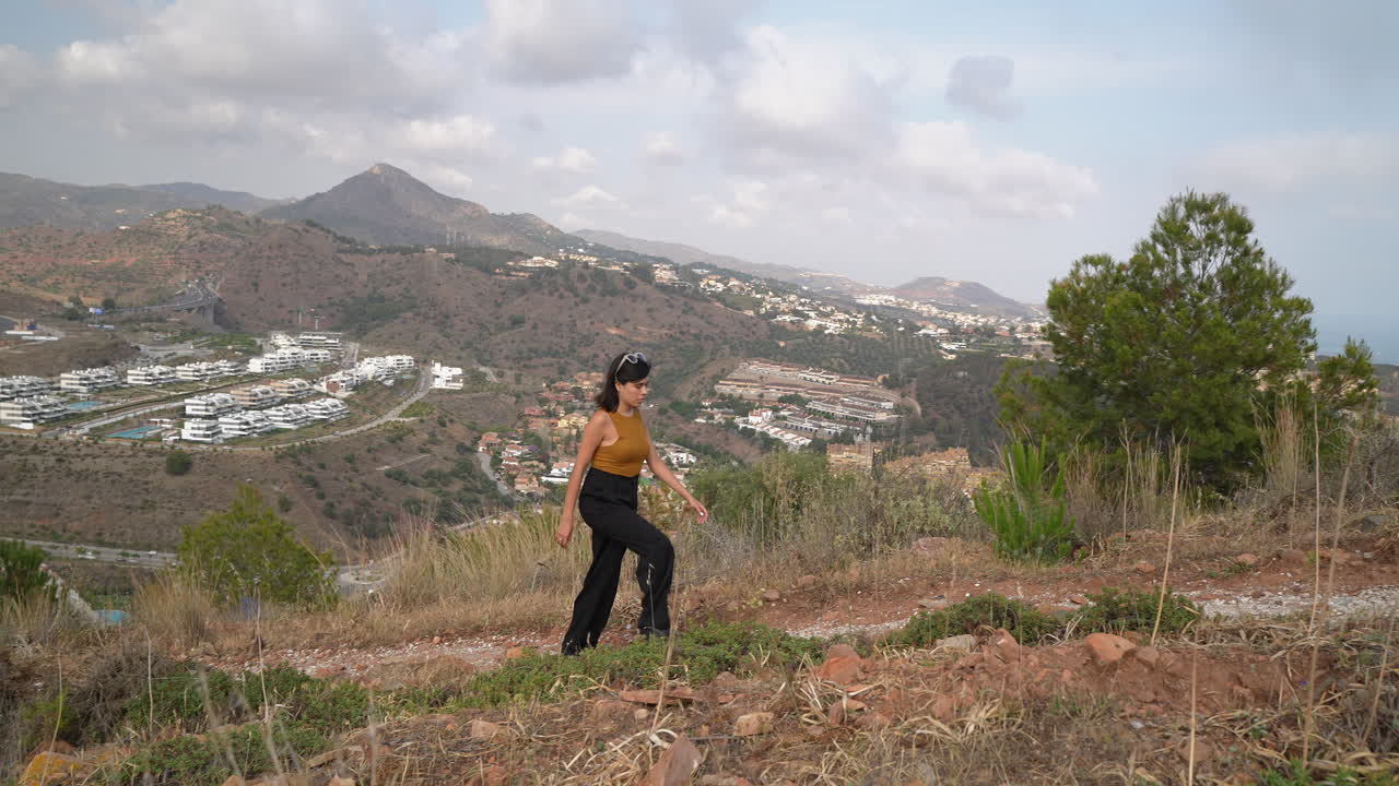 hermosa mujer milenaria caminando por el sendero de la montaña en un día soleado