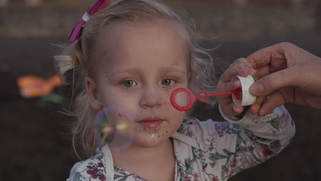 una cámara lenta de una niña adorable que está soplando burbujas de jabón