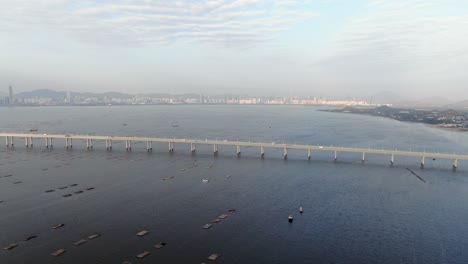 puente de la bahía de hong kong shenzhen con edificios tin shui wai en el horizonte y piscinas de cultivo de peces y ostras, vista aérea