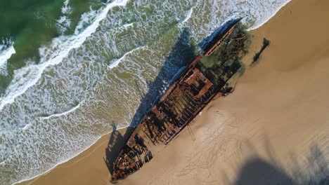 un drone de 4k ariel gira alrededor del naufragio de maheno por el océano azul-verde en la playa de la isla de k'gari frasier, queensland, australia.
