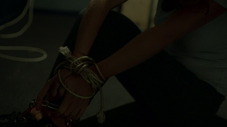 Tied up woman pulling on chains wrapped around her legs