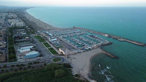 Dolly-in-shoot-of-a-seaside-marina-at-sunset,-with-the-city-skyline