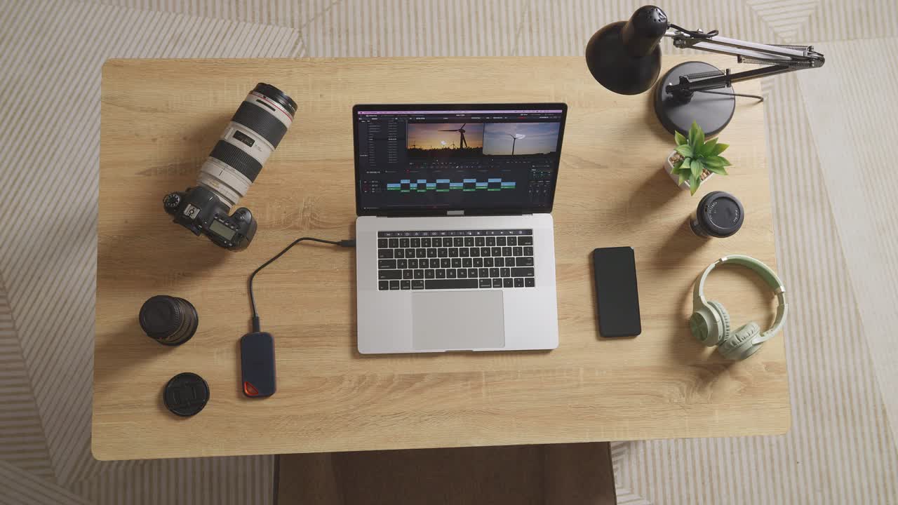vista superior zoom en la toma de una computadora portátil que muestra la edición de video en la mesa con teléfono inteligente y cámara en el espacio de trabajo en casa