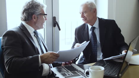 two mature business partners at table with laptop