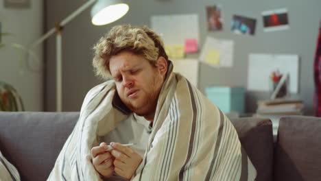 sick man holding thermometer and calling doctor at home