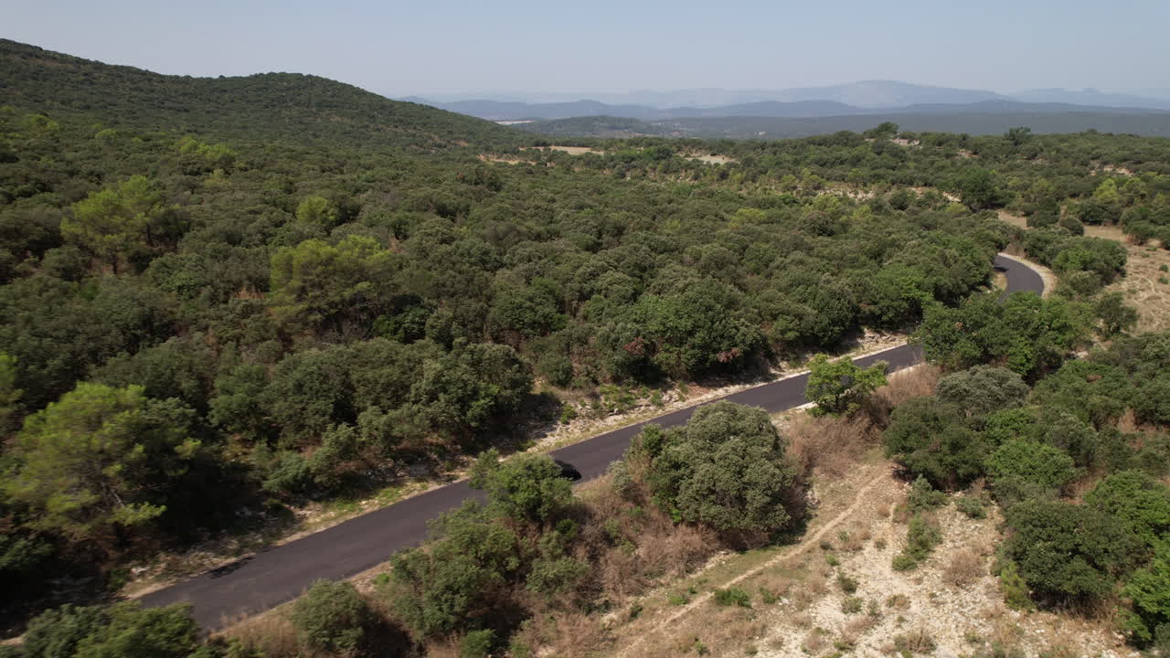 fotografía aérea de una carretera en un bosque con un coche eléctrico francia día soleado