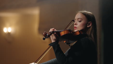 inspired and talented woman fiddler in symphonic orchestra on scene of music hall