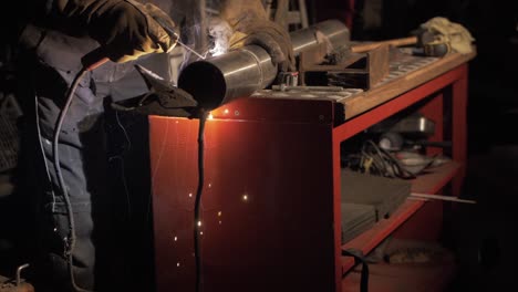 welder welding stainless steel pipe together using shielded metal arc welding