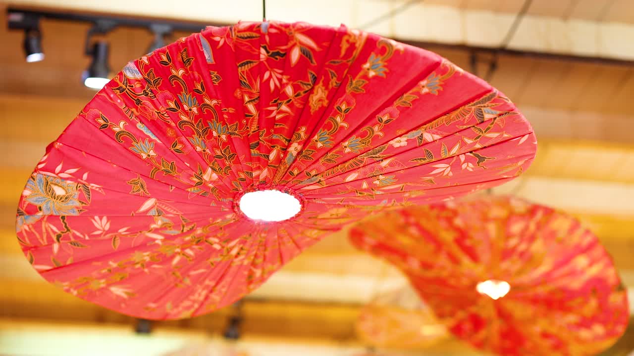 las linternas rojas vibrantes se balancean suavemente bajo la iluminación cálida en un restaurante de phuket, creando una atmósfera animada y acogedora