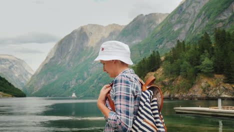 a woman with rbczak walks against the backdrop of a beautiful landscape in norway - a beautiful fjor