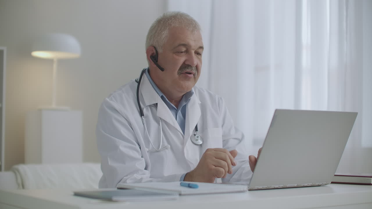 un medico di sesso maschile allegro sta comunicando online con colleghi o pazienti tramite laptop utilizzando una videochiamata
