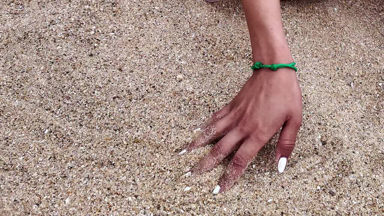 바가에 있는 한 여인이 아름다운 모래 해변을 그녀의 손으로 천천히 만지고 있다.