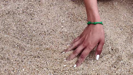 una mujer en la orilla de la mar acaricia la belleza de la playa de arena con su mano lentamente, francia