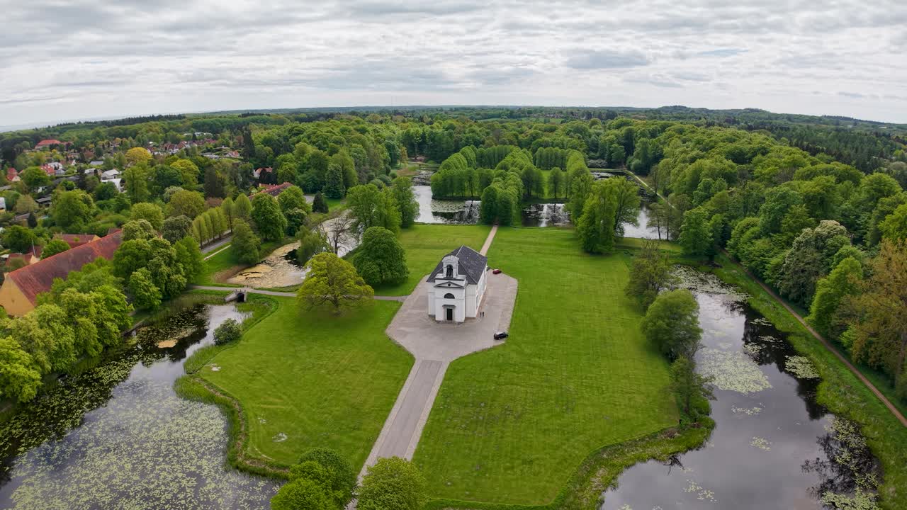 Aerial drone view of Hørsholm Kirke Park surrounded by manicured lawns, trees, and walking paths in a lush green park, Hørsholm Denmark