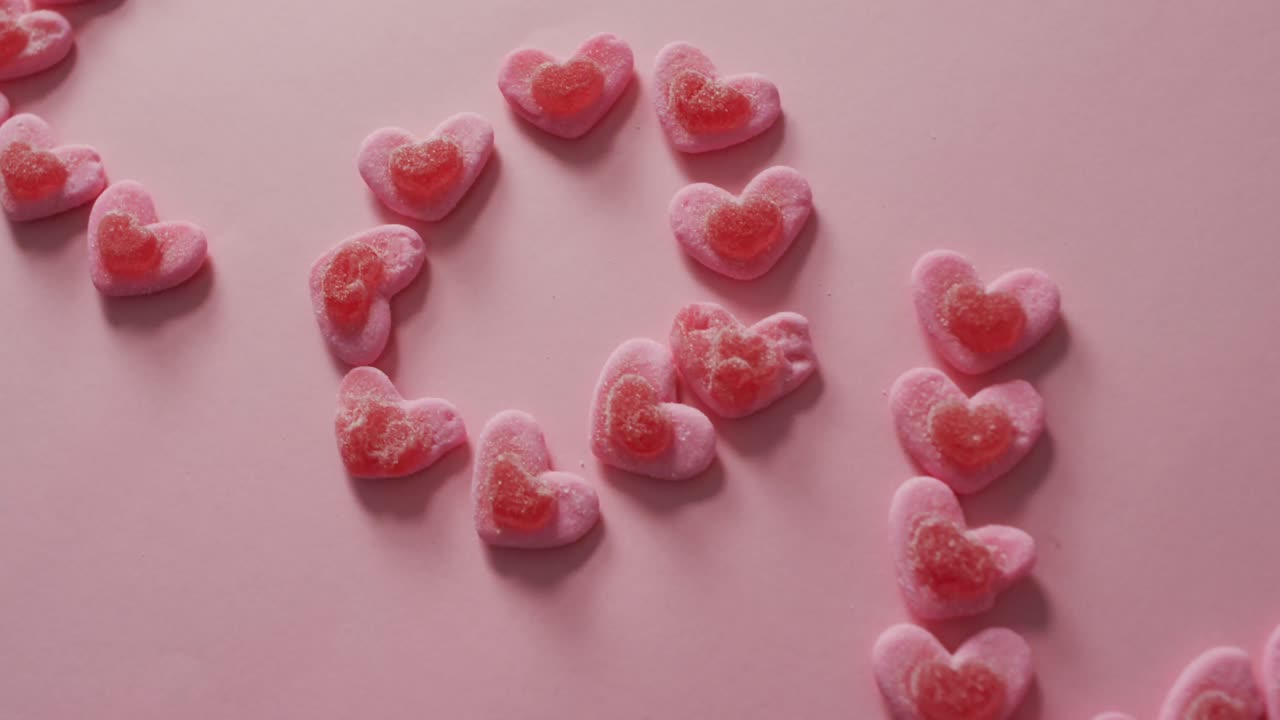 Love text of heart shape sweets on pink background at valentine's day