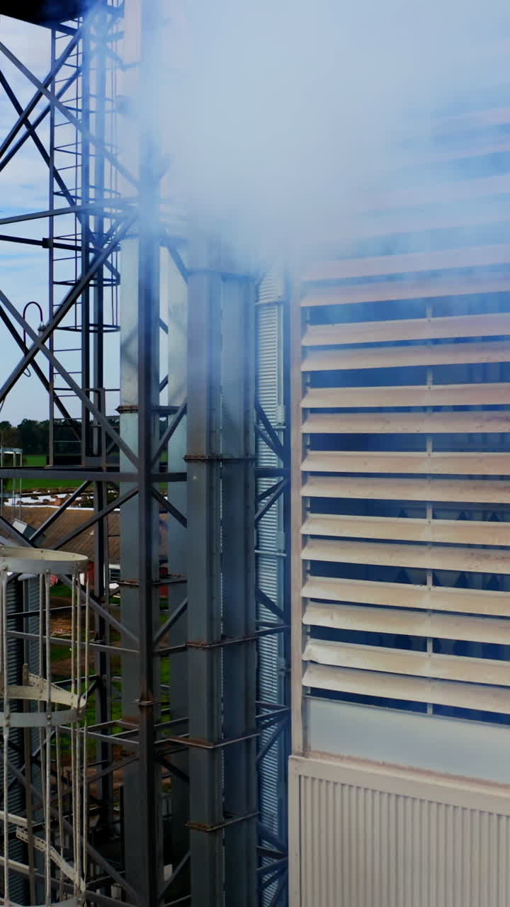 Exterior of modern industrial plant. White smoke filling in the air from warehouse. Close-up. Pollution the environment. Camera rising up. Vertical video