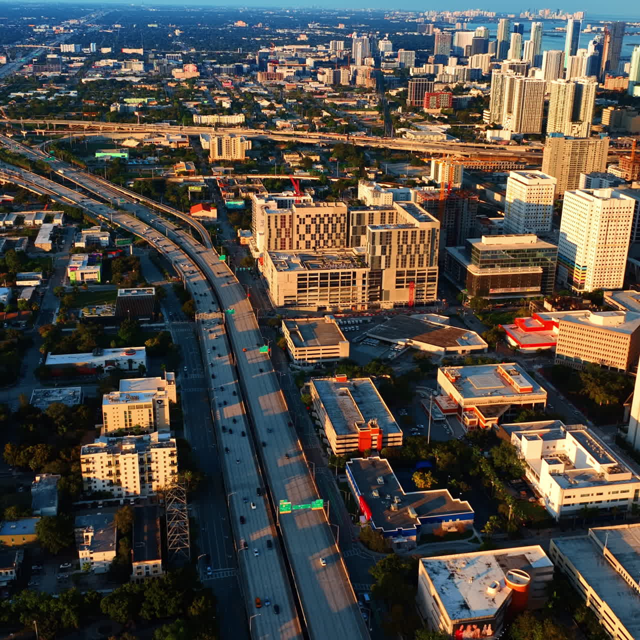 Beautiful scenery of sunny Miami at sundown. Drone going down above the highways with transport moving by.