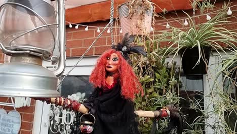 magical red haired handmade witch on broomstick hanging with lantern and plants in home garden sanctuary