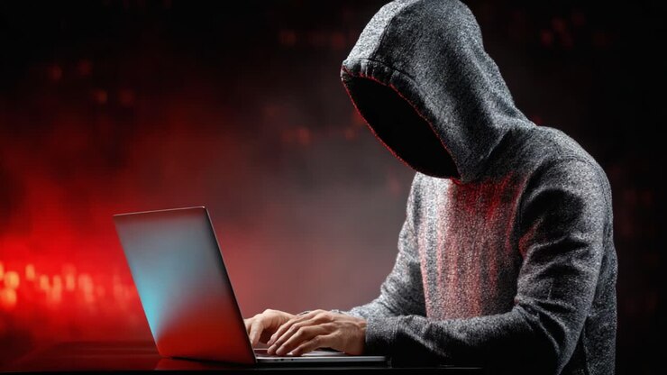 Una figura ombrosa con un cappuccio che digita intensamente su un laptop, circondata da un alone di luci rosse, cattura l'essenza del mistero e dell'intrigo nel mondo digitale