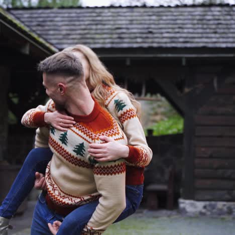 happy young lovely couple having fun near wooden house in the park. man piggybacking girl, running happily. guy whirling woman around. love story video
