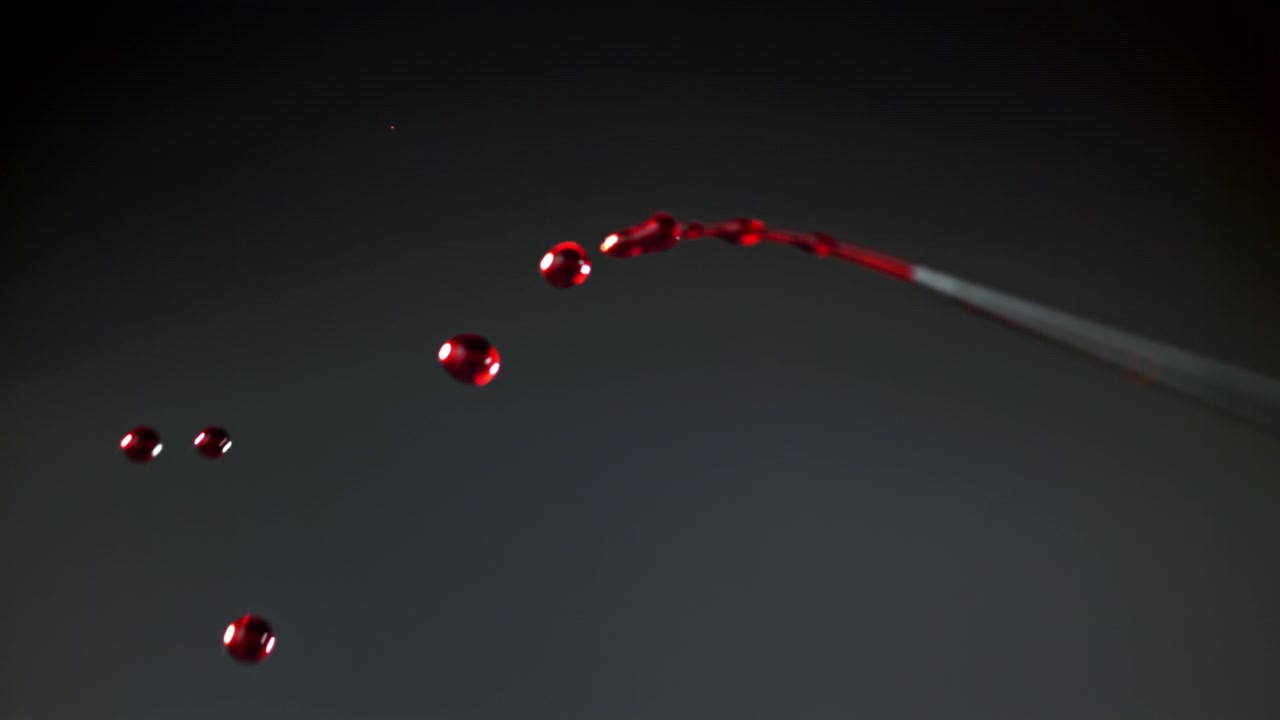 Red Liquid Drops Dripping from a Pipette in Slow Motion
