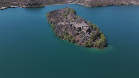 aerial view over small woodland island in the stunning green lake turquoise waters in the taurus mountains of turkey