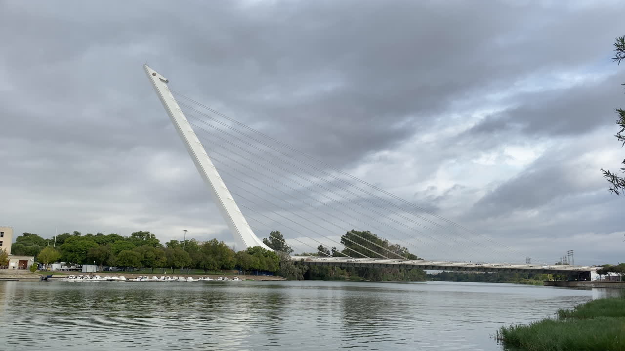 Stor, hvid bro i bueform strækker sig hen over hovedet fra flodbredden og spejler sig blødt i det grønlige vand nedenunder