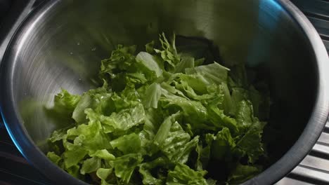 close up of chef dropping vegetables in a metal bowl full of tuna to prepare a tuna salad