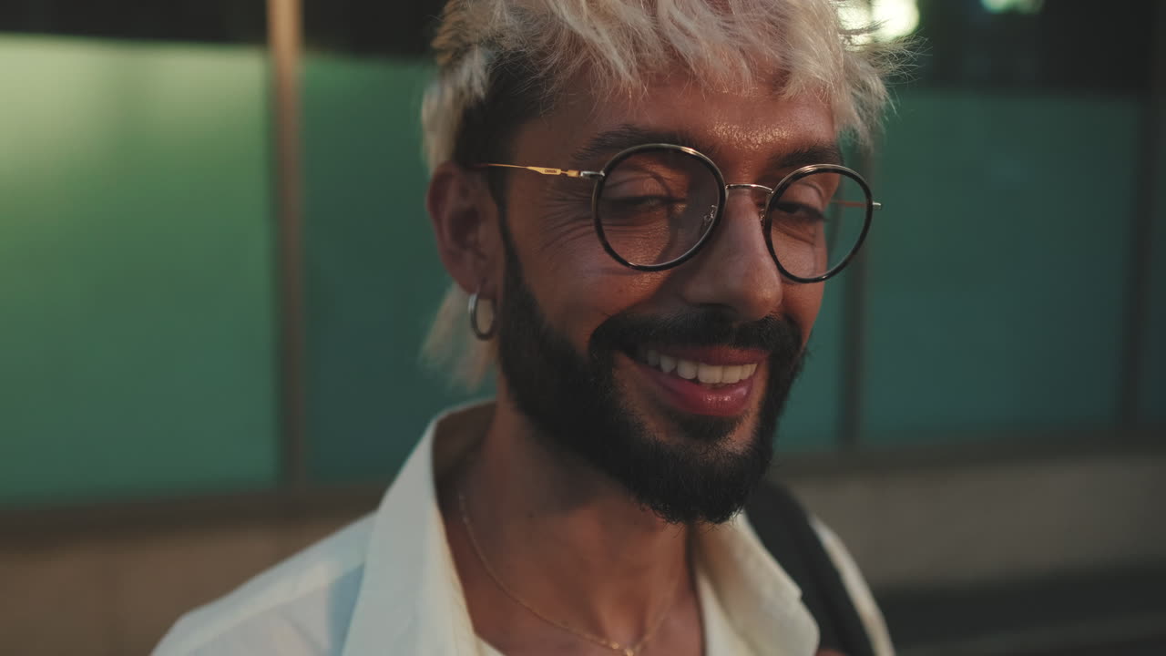 Young Man with Bleached Hair and Glasses Smiling at Night