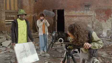 close up view of cameraman setting up a camera in a ruined building and then looks at the camera