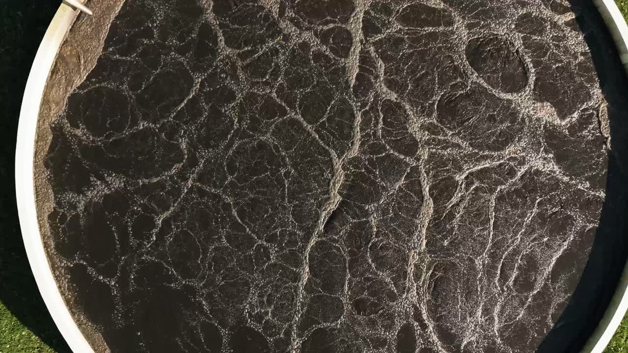 Aerial view of wastewater treatment plant, dark purification tank symbolizing clean water efforts.