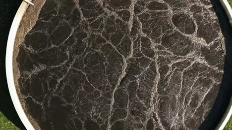 aerial view of wastewater treatment plant, dark purification tank symbolizing clean water efforts.