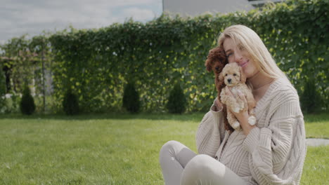 portrait of a young pregnant woman with puppies in her arms. sitting on the lawn in the backyard of his house